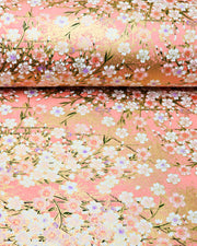 Japanese chiyogami paper featuring light pink and white cherry blossoms on a pink background with metallic gold details. Some of the white cherry blossoms have purple centers.