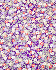Japanese chiyogami paper featuring purple, red, white, and yellow plum blossoms on a purple background with metallic gold accents.