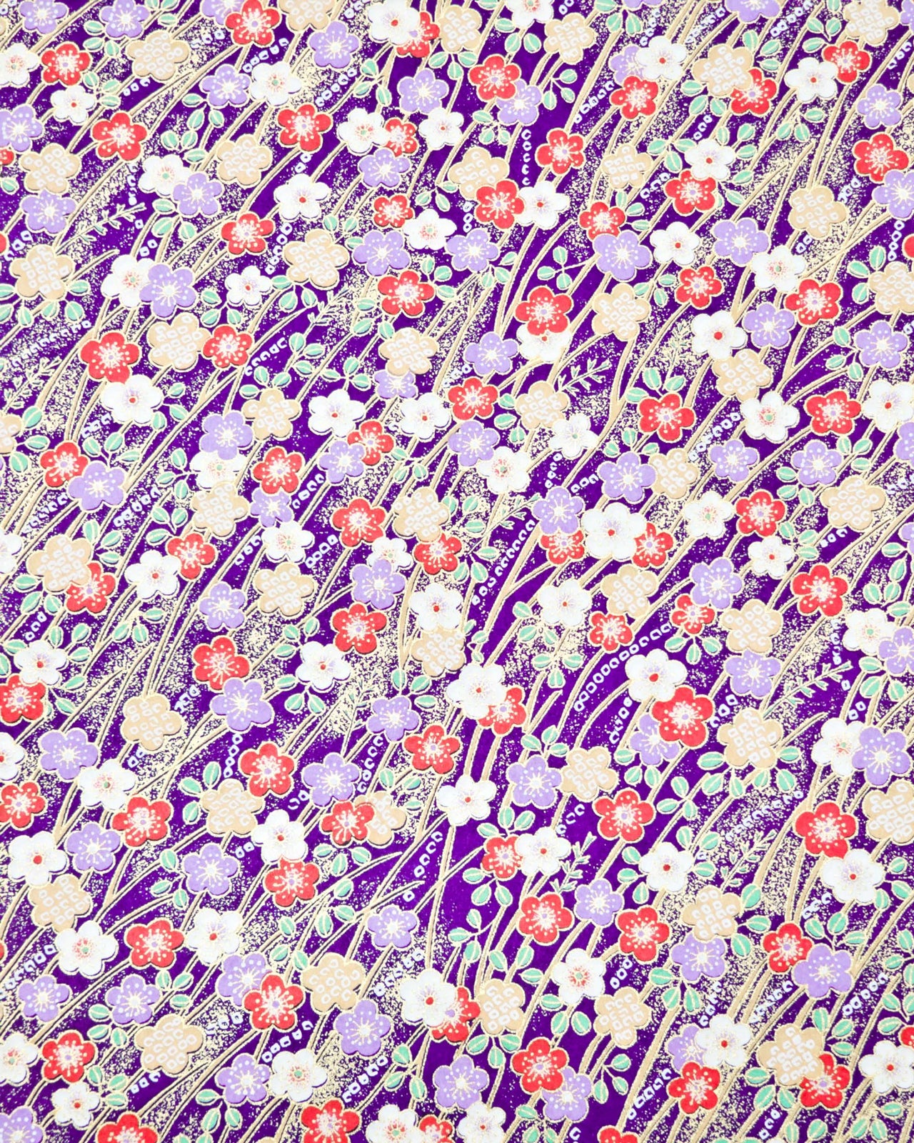 Japanese chiyogami paper featuring purple, red, white, and yellow plum blossoms with beige branches and light green leaves on a dark purple background with metallic gold details.