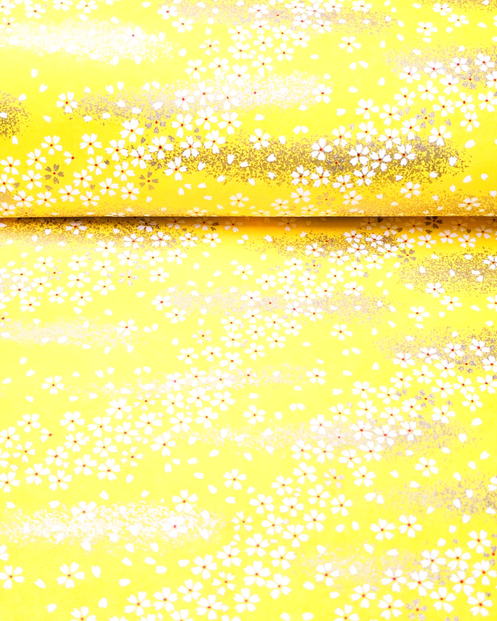 Japanese chiyogami paper featuring small metallic gold and white cherry blossoms on a yellow background.