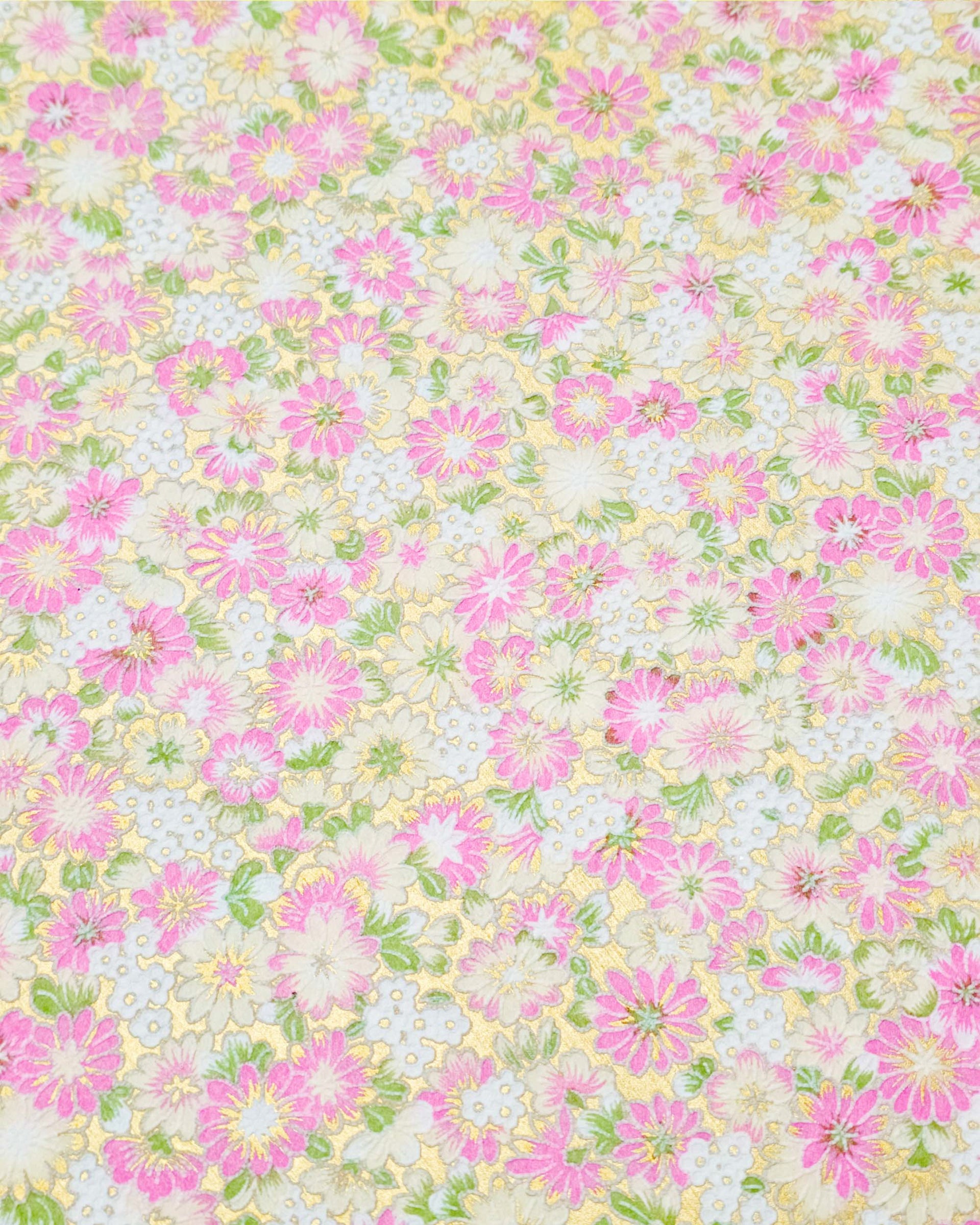 Japanese chiyogami paper featuring textured white and pink mum flowers on a metallic gold background. The lines on the flowers are raised.