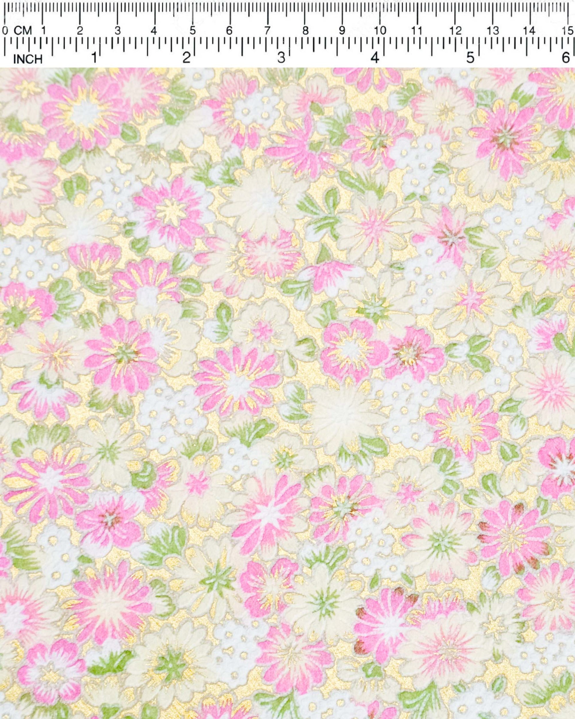 Japanese chiyogami paper featuring textured white and pink mum flowers on a metallic gold background. The lines on the flowers are raised.
