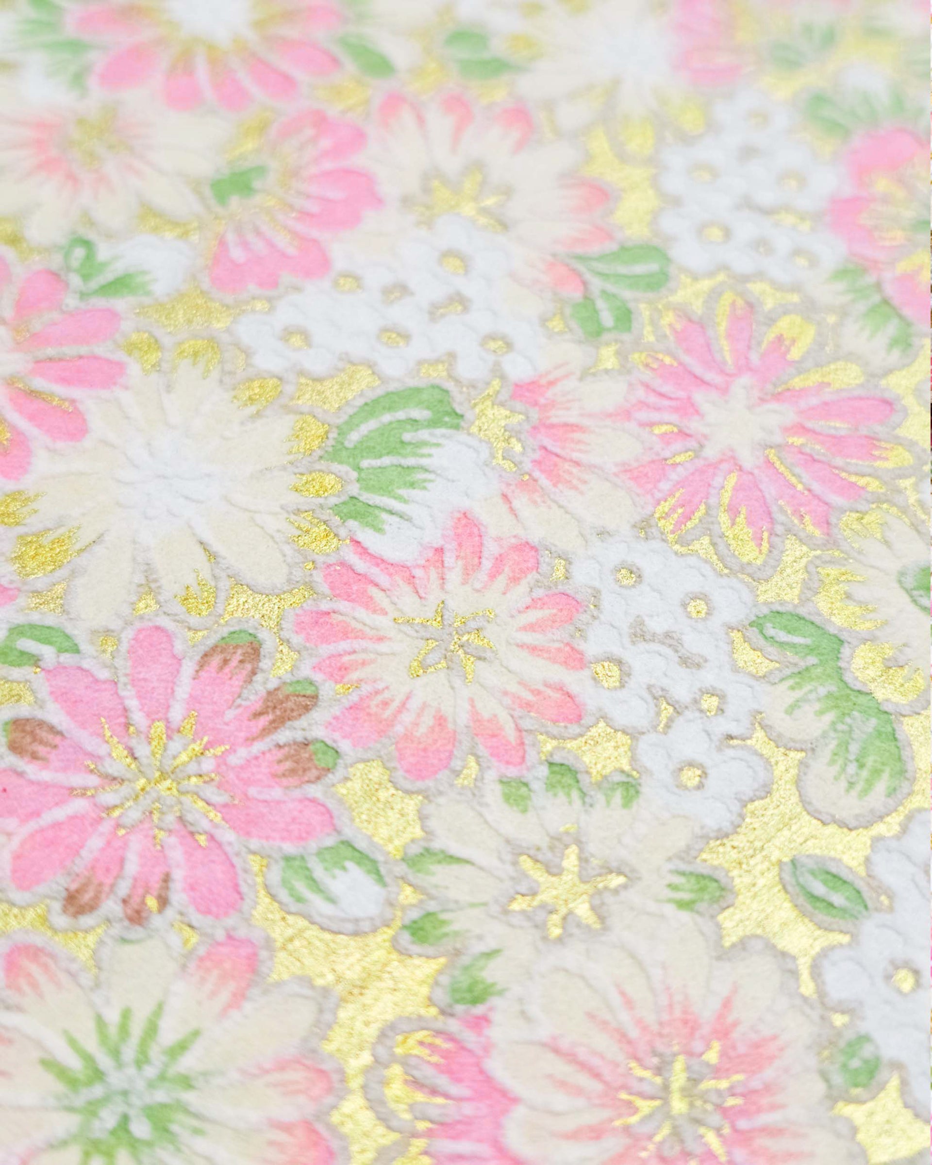 Japanese chiyogami paper featuring textured white and pink mum flowers on a metallic gold background. The lines on the flowers are raised.