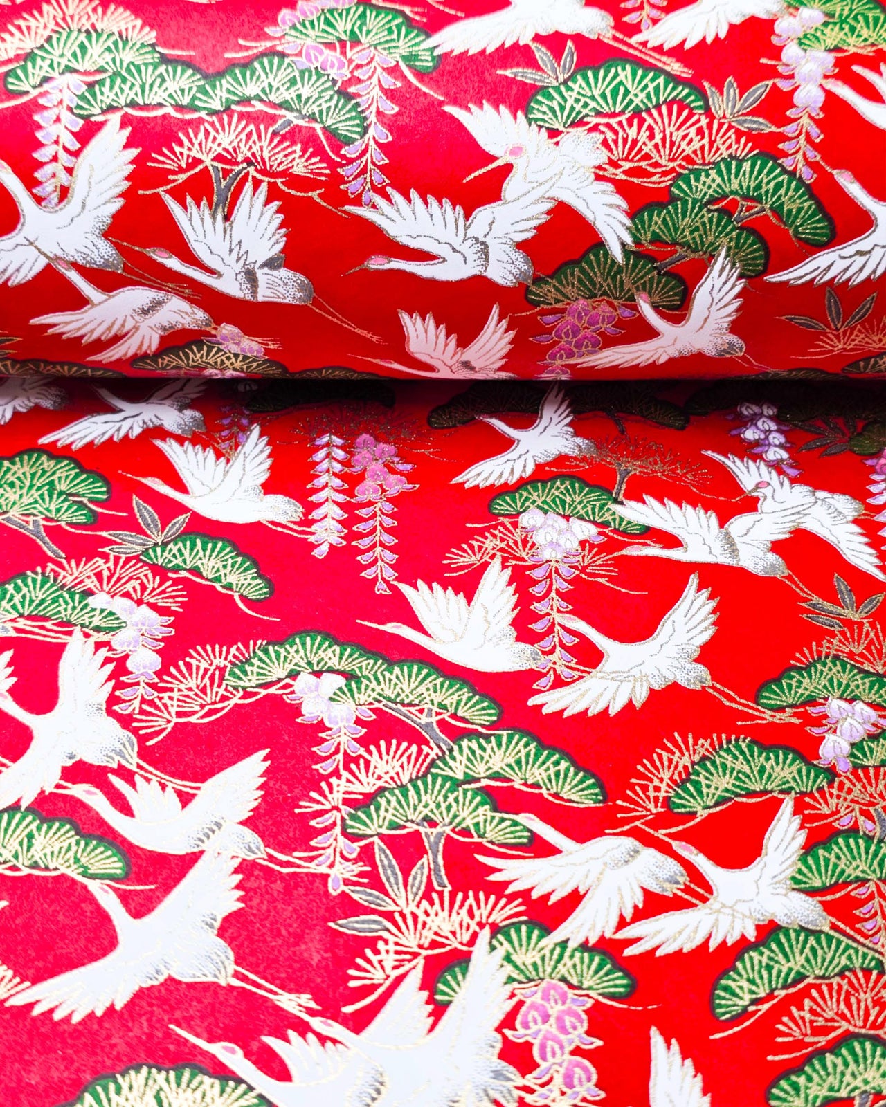 Japanese chiyogami paper featuring white flying cranes and purple wisteria on a red background with metallic gold accents.