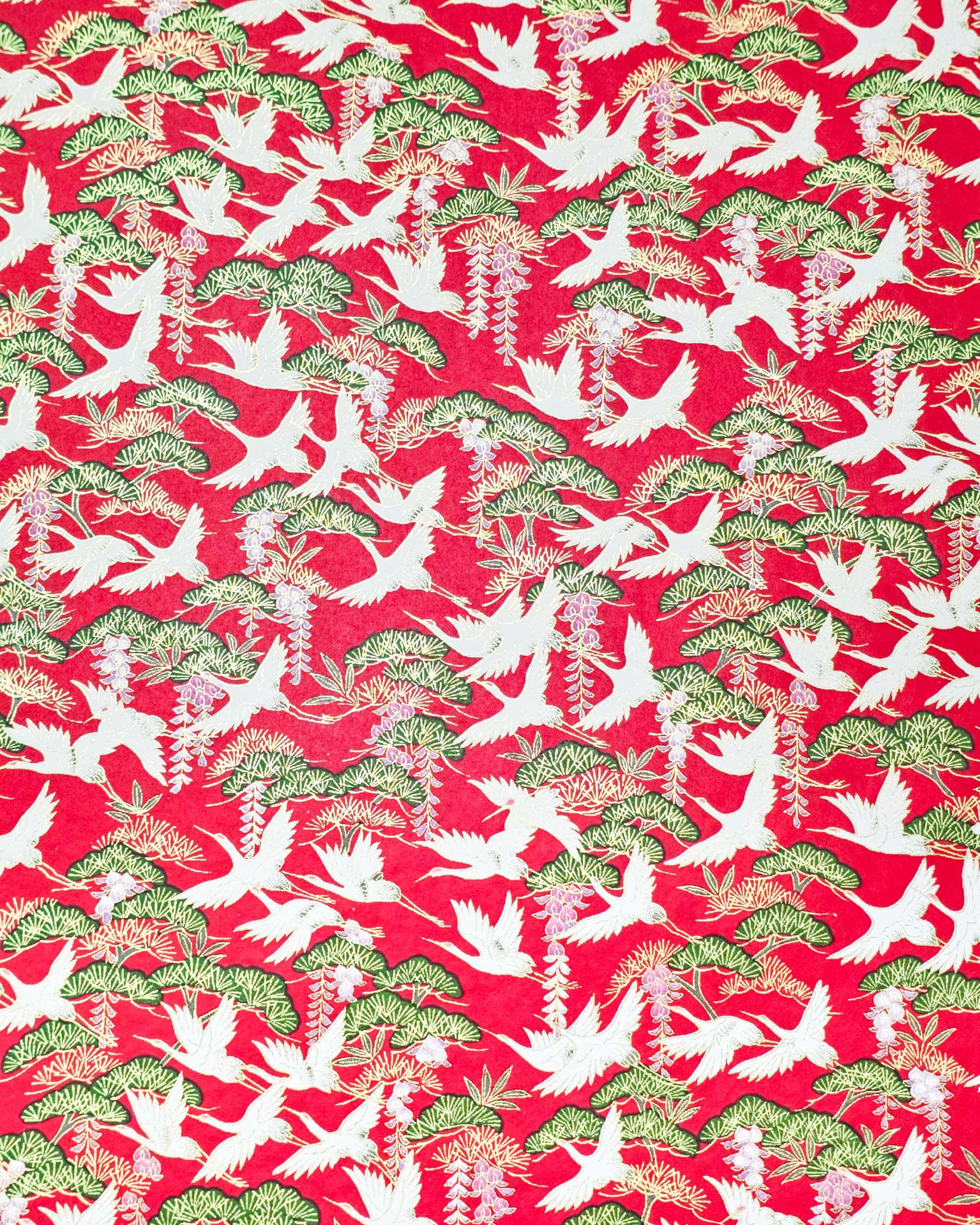 Japanese chiyogami paper featuring white flying cranes, purple and white wisteria, and green pine on a pearlescent red background with metallic gold details.