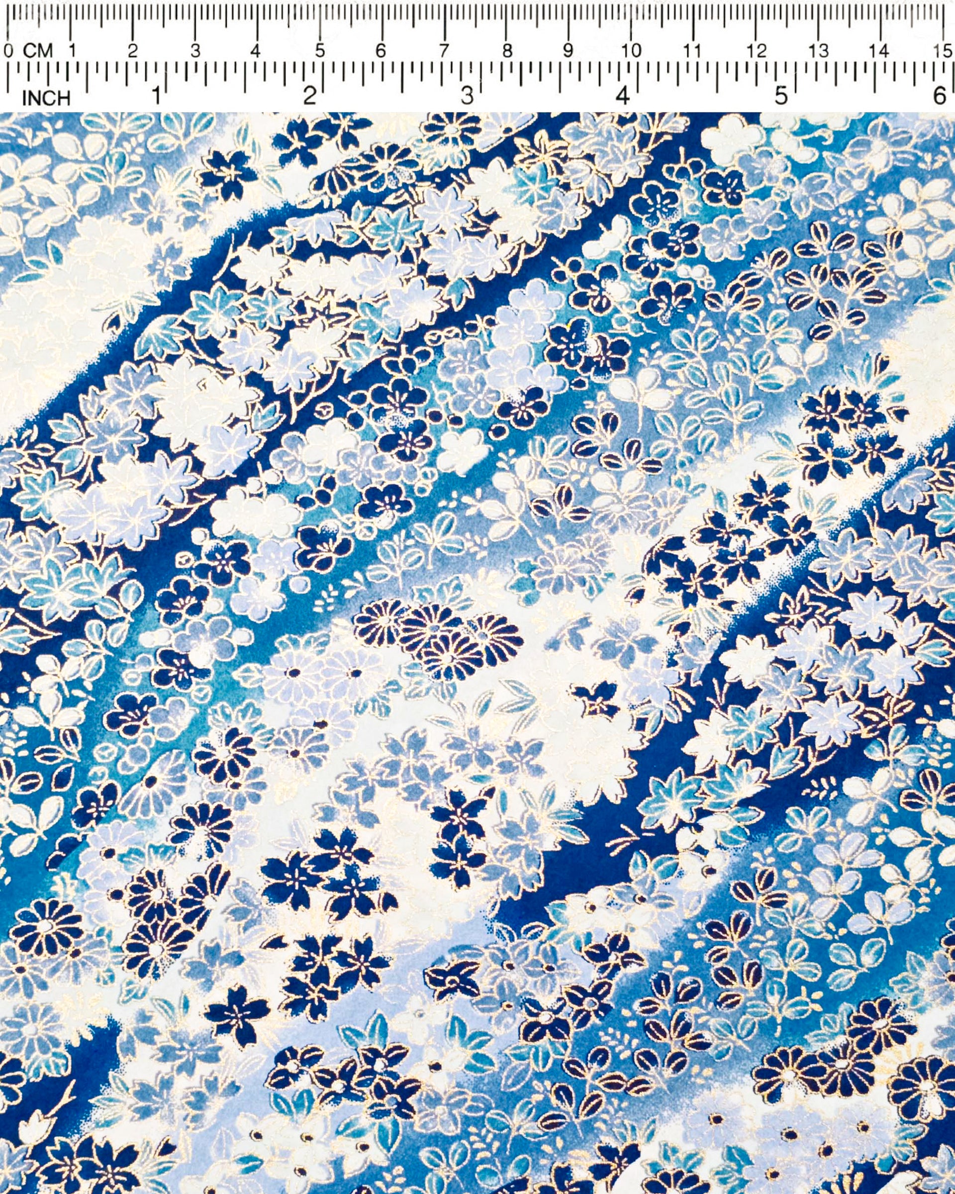 Japanese chiyogami paper featuring an assortment of blue and white traditional Japanese flowers and leaves on a blue and white gradient background with metallic gold details.