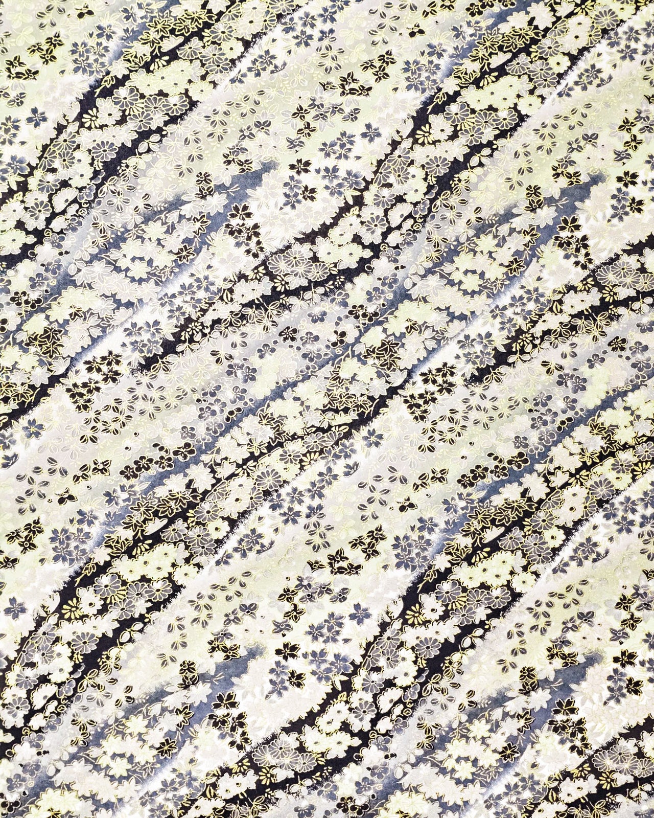 Japanese chiyogami paper featuring an assortment of gray and cream traditional Japanese flowers and leaves on a white, gray, and black gradient background with metallic gold details.
