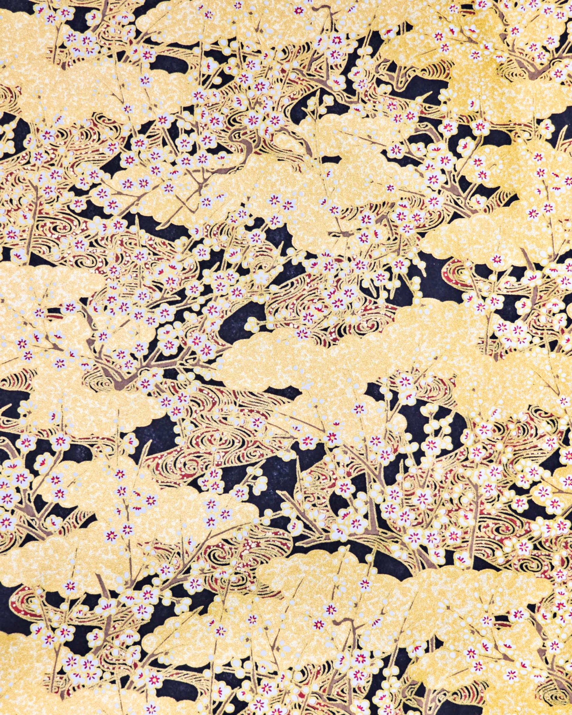 Japanese chiyogami paper featuring small white plum blossom branches with red and gold water ripples and large gold clouds on a black background with metallic gold details. 