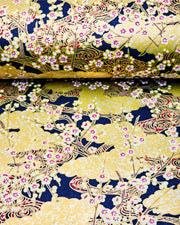 Japanese chiyogami paper featuring white plum blossom branches on a black and gold background with metallic gold accents.