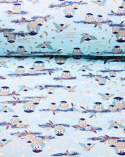 Japanese chiyogami paper featuring blue and gray owls perched on branches and flying around with a light blue night sky background adorned with small metallic gold stars and crescent moons.