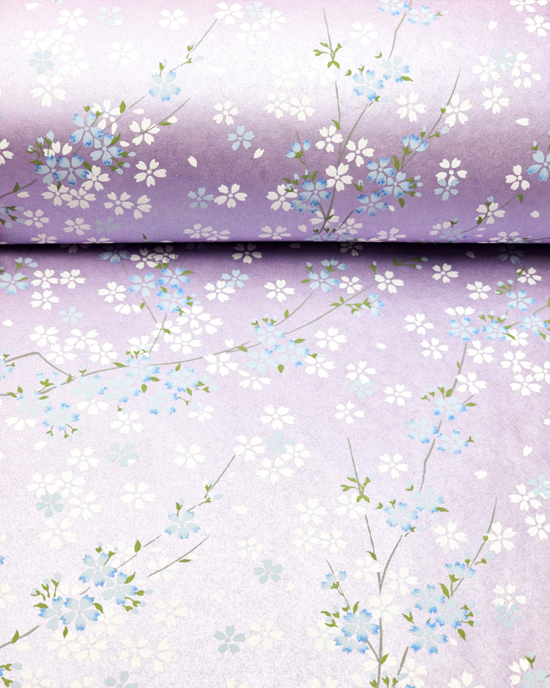 Japanese chiyogami paper featuring light blue and white cherry blossoms with green leaves and branches on a pearlescent light purple background.