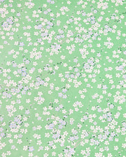 Japanese chiyogami paper featuring light blue and white cherry blossoms with green leaves and branches on a pearlescent green background.