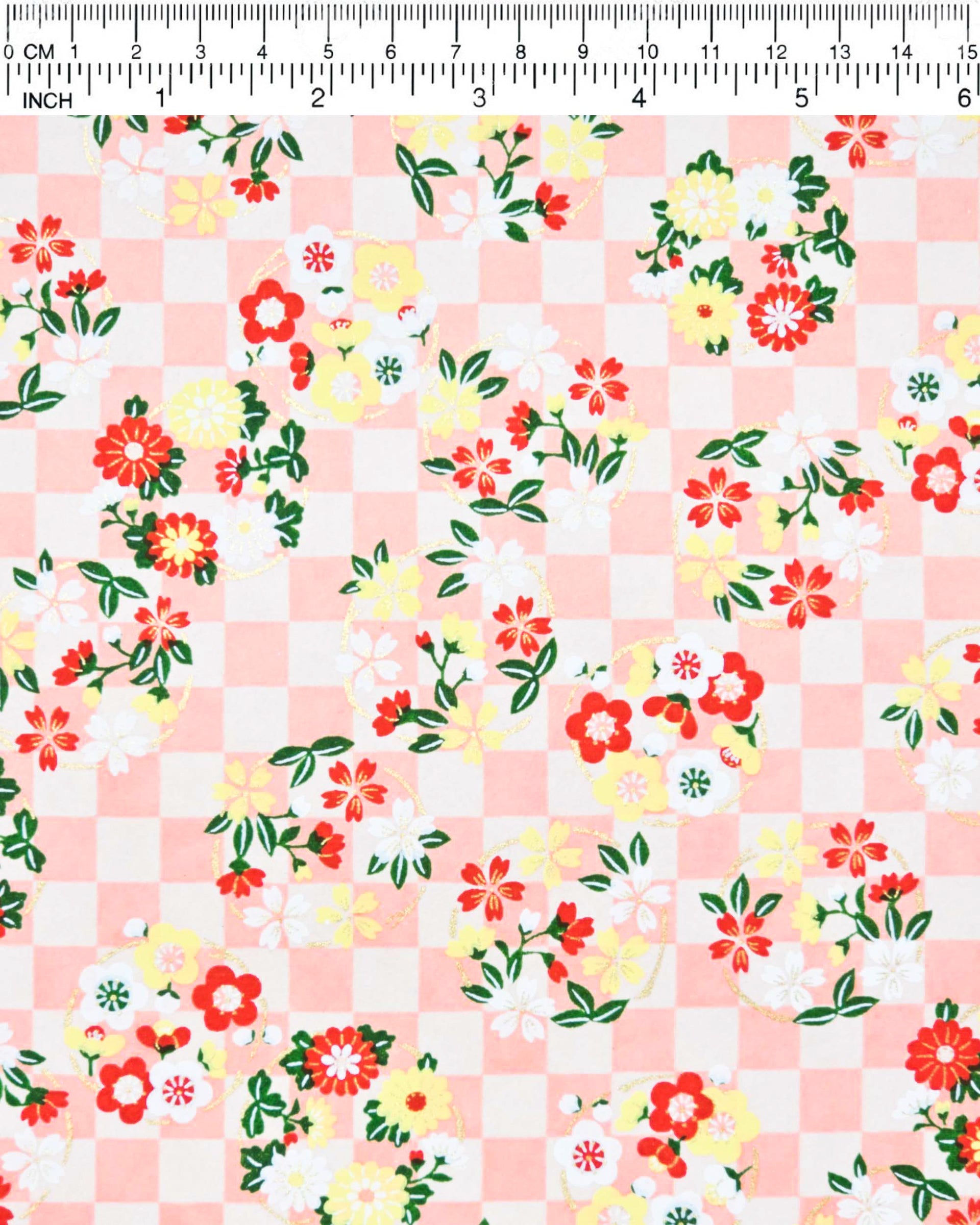 Japanese chiyogami paper featuring yellow, red, and white flowers with green leaves on a light orange ichimatsu (checkered) background with metallic gold accents.
