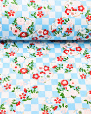 Japanese chiyogami paper featuring light pink, red, and white flowers with green leaves on a light blue ichimatsu (checkered) background with metallic gold accents.