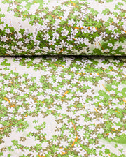 Japanese chiyogami paper featuring green and white cherry blossoms with light green branches on a green background with metallic gold accents.