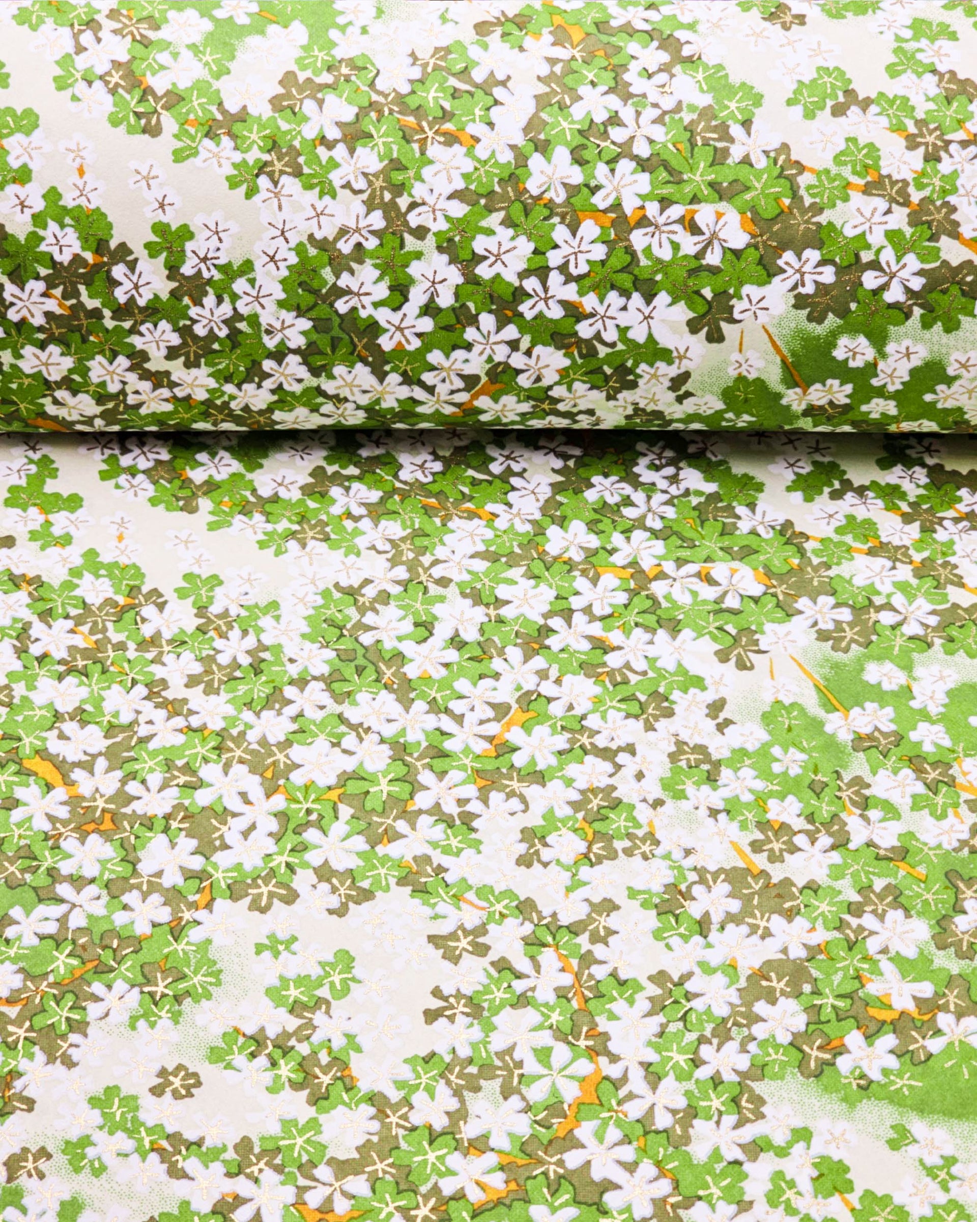 Japanese chiyogami paper featuring green and white cherry blossoms with light green branches on a green background with metallic gold accents.