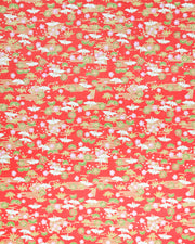 Japanese chiyogami paper featuring small white folded origami cranes with green pine and pink plum blossoms on a red background with metallic gold accents.

