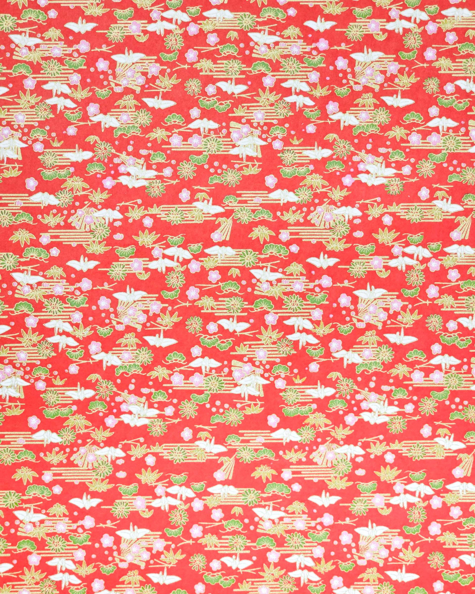 Japanese chiyogami paper featuring small white folded origami cranes with green pine and pink plum blossoms on a red background with metallic gold accents.
