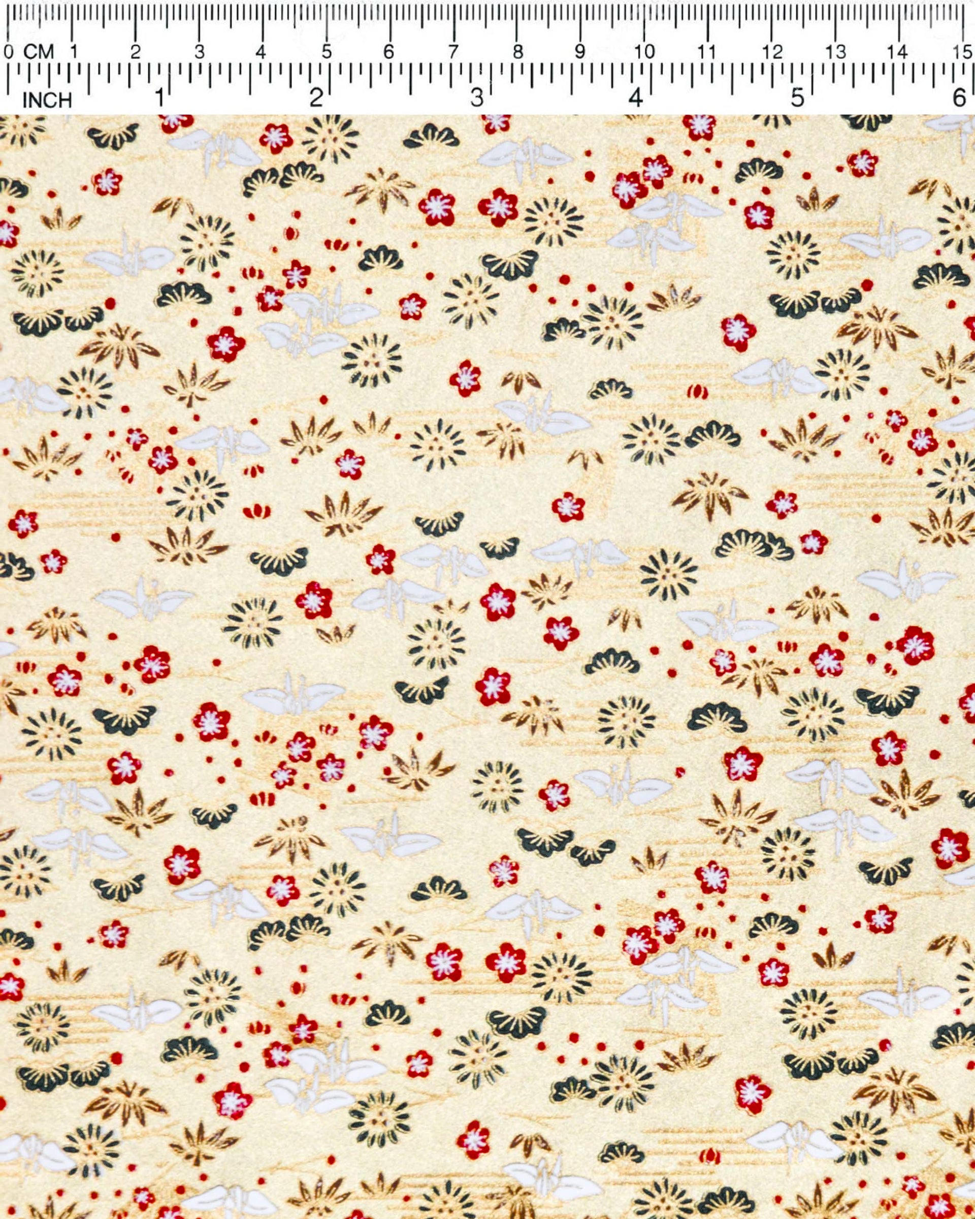 Japanese chiyogami paper featuring small white folded origami cranes with green pine and red plum blossoms on a metallic gold background.