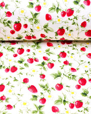 Japanese chiyogami paper featuring red strawberries with green leaves and white flowers with yellow centers on a pearlescent white background, shown rolled to highlight the design.