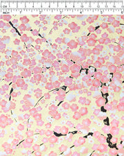 Japanese chiyogami paper featuring pink and white plum blossom trees with dark brown branches on a metallic gold background, shown next to a ruler for size reference.