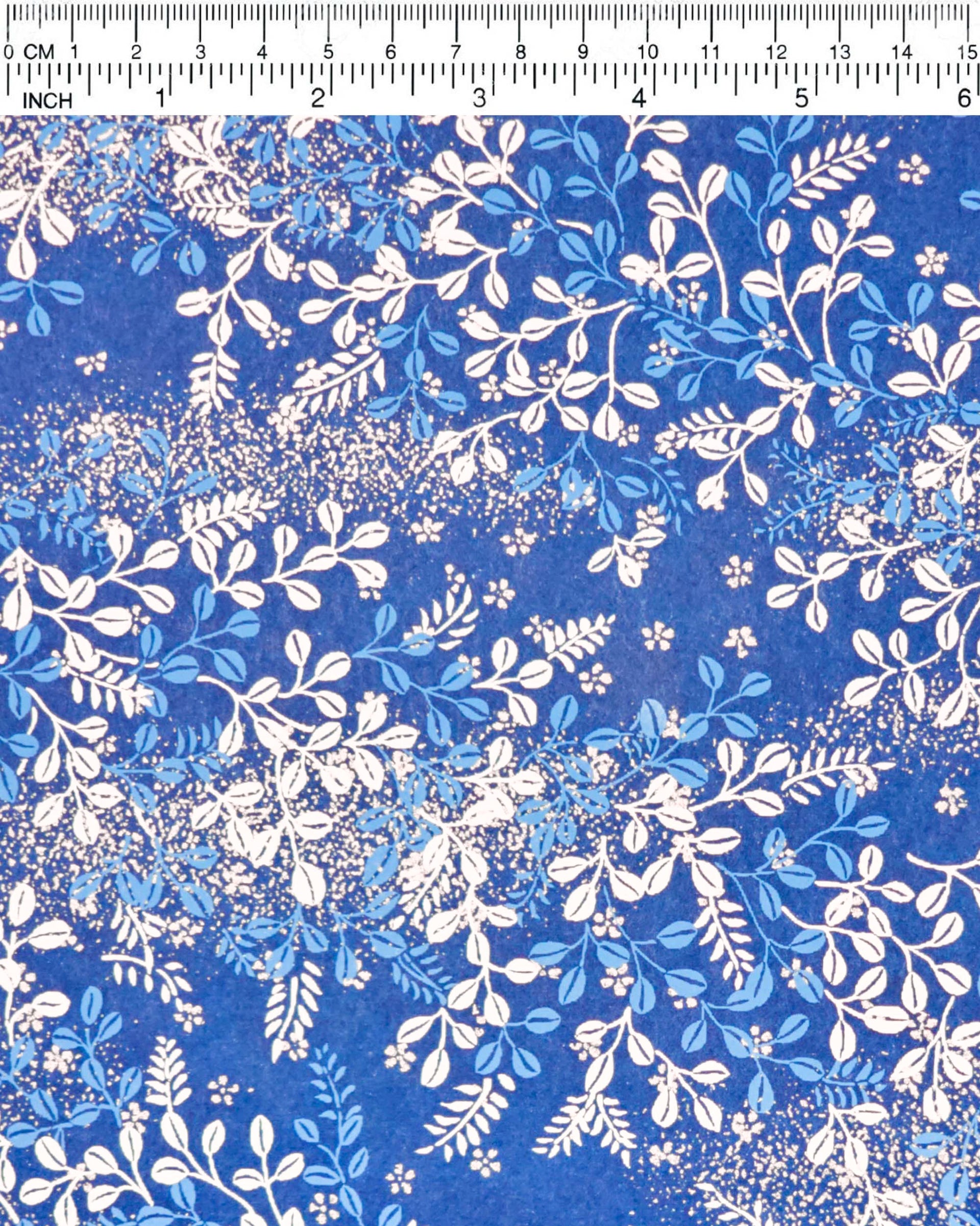 Japanese chiyogami paper featuring blue and white hagi (bush clover) on a blue background with metallic gold details, shown next to a ruler for size reference.