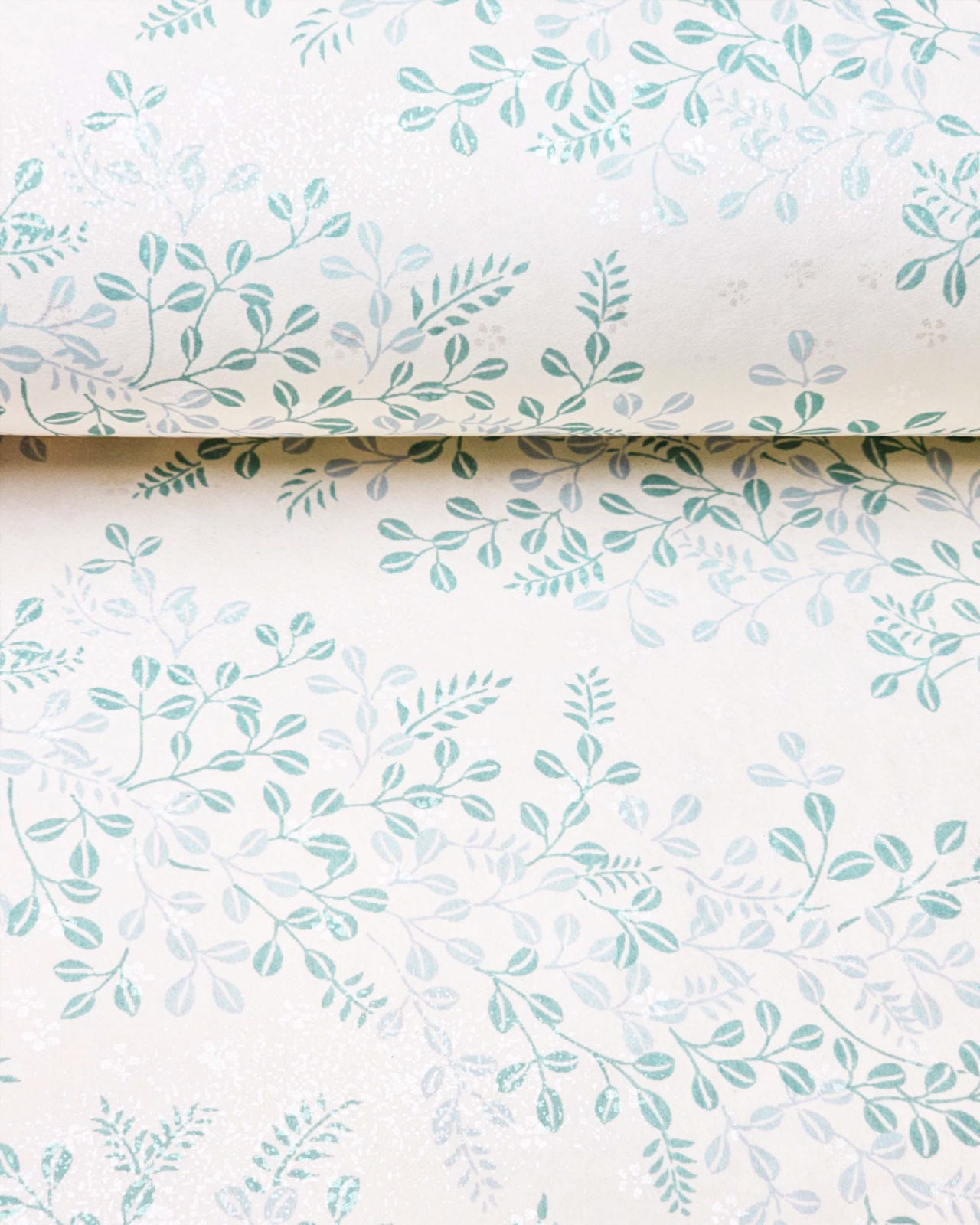 Japanese chiyogami paper featuring light blue and turquoise hagi (bush clover) on a light cream background with metallic silver details, shown rolled to highlight the design.