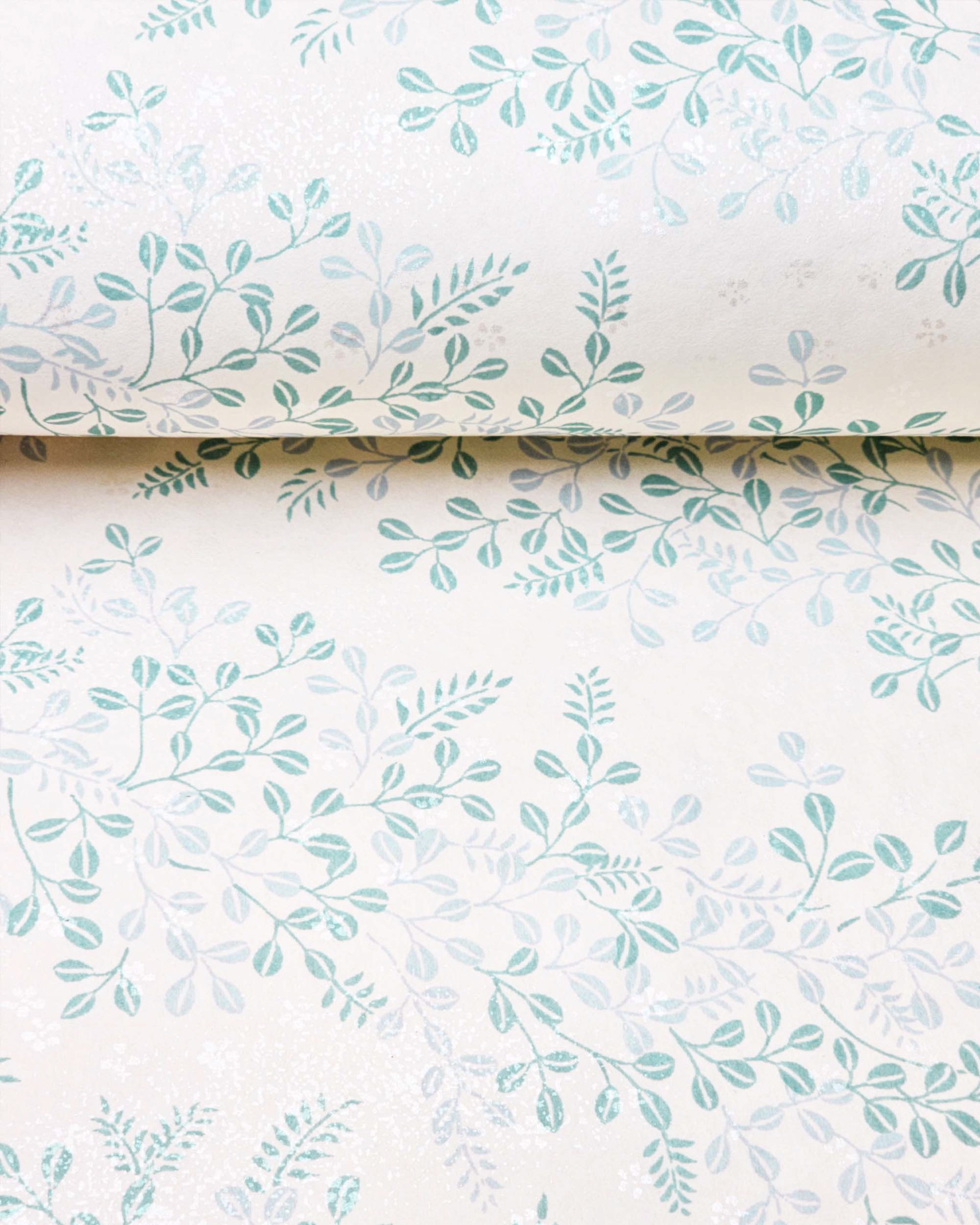 Japanese chiyogami paper featuring light blue and turquoise hagi (bush clover) on a light cream background with metallic silver details, shown rolled to highlight the design.