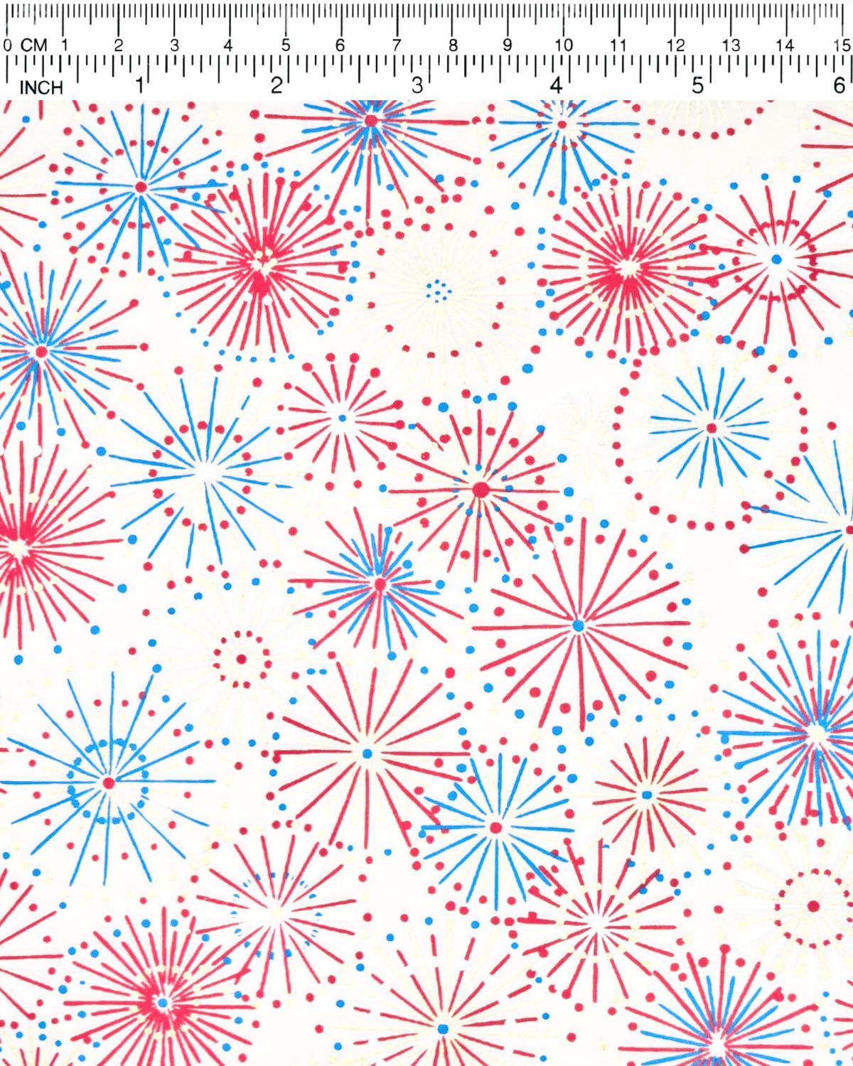 Japanese chiyogami paper featuring colorful red, blue, pink, and white exploding fireworks on a white background with metallic gold details, shown next to a ruler for size reference.