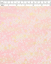Japanese chiyogami paper featuring small white and gold cherry blossoms on a pink background with metallic gold details, shown next to a ruler for size reference.