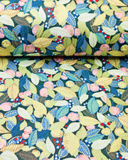 Japanese chiyogami paper featuring green, blue, and yellow leaves with pink persimmon fruits on a dark green background with metallic gold details, shown next to a ruler for size reference.