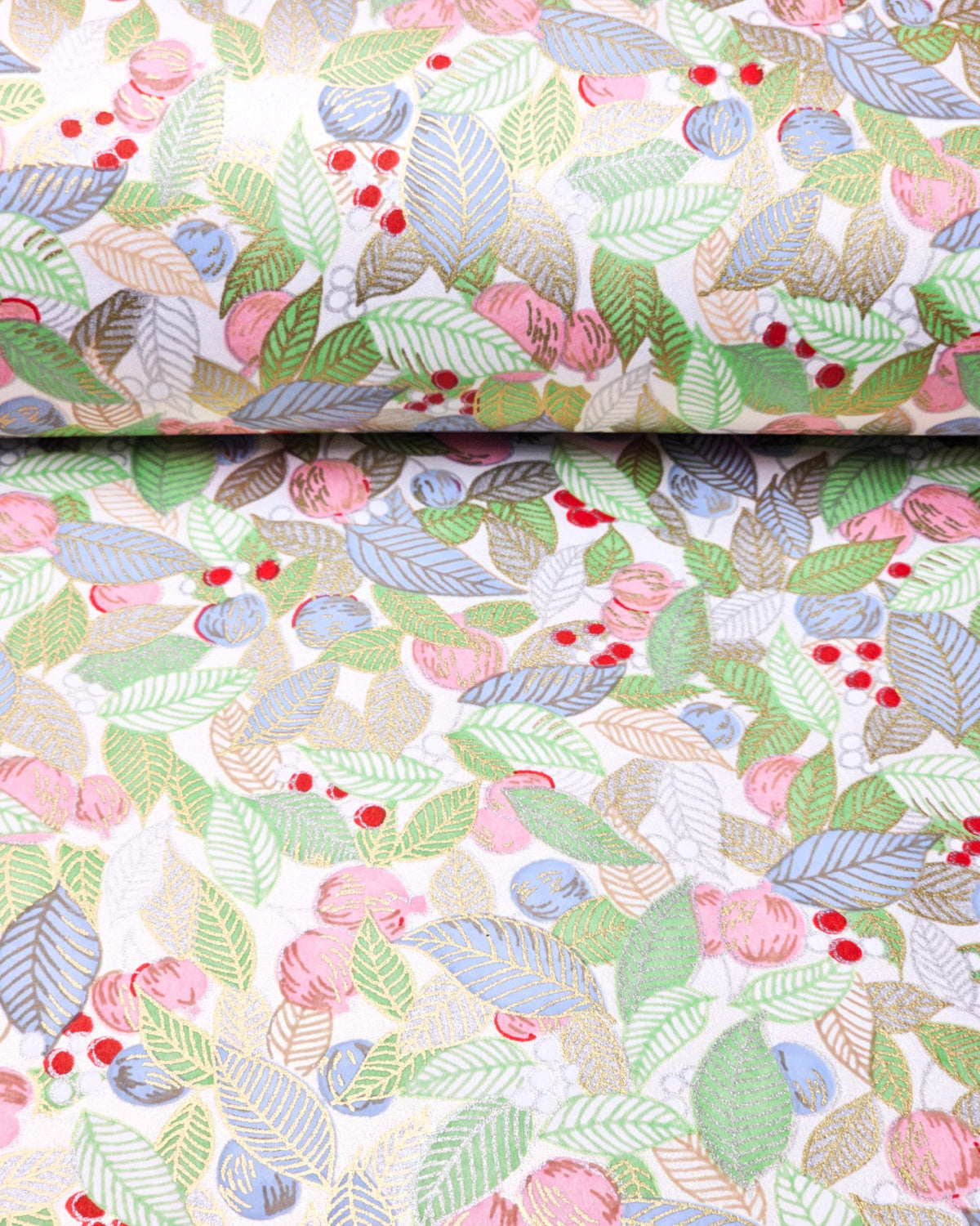 Japanese chiyogami paper featuring green, blue, and silver leaves with pink persimmon fruits on a white background with metallic gold details, shown rolled to highlight the design.