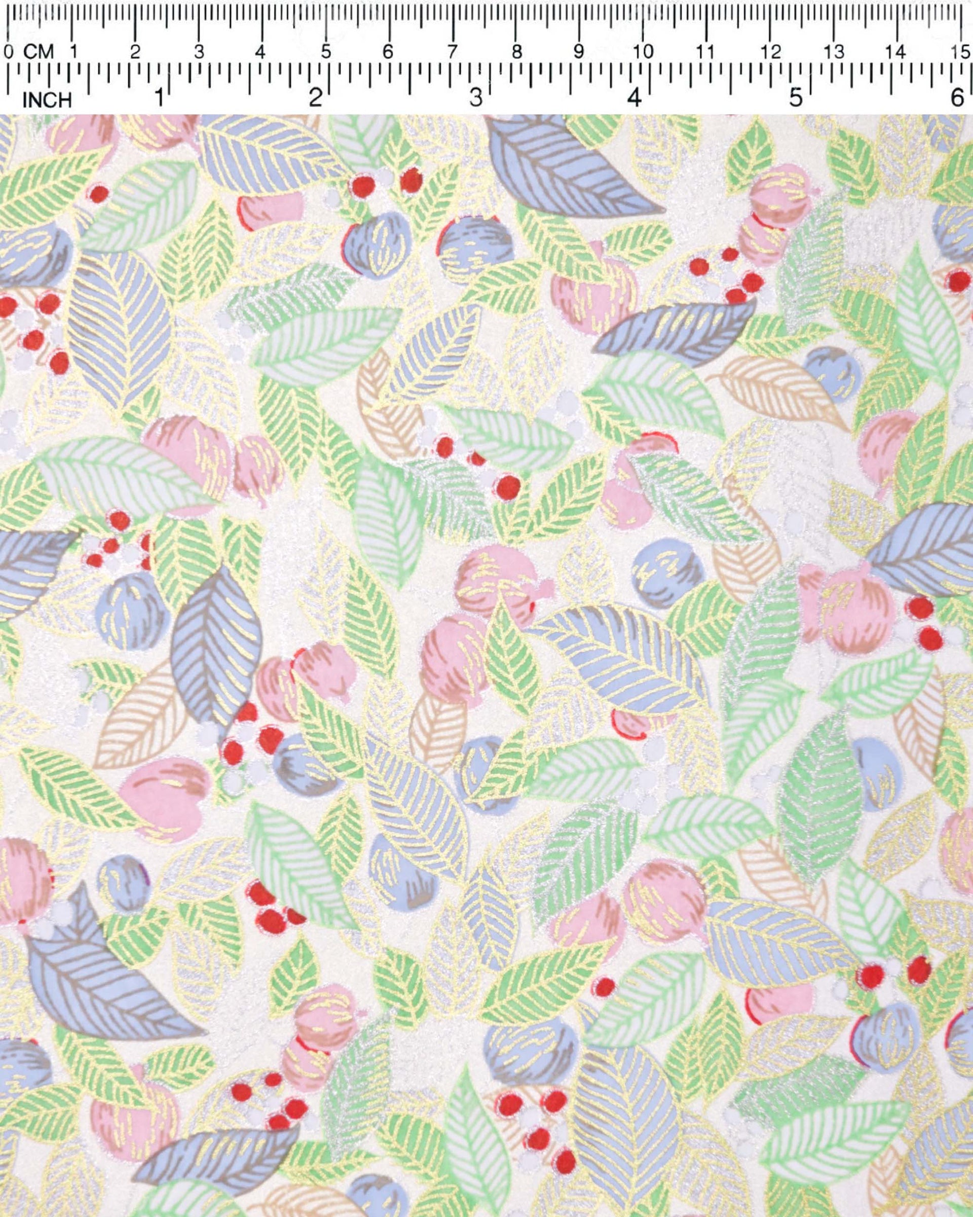 Japanese chiyogami paper featuring green, blue, and silver leaves with pink persimmon fruits on a white background with metallic gold details, shown next to a ruler for size reference.