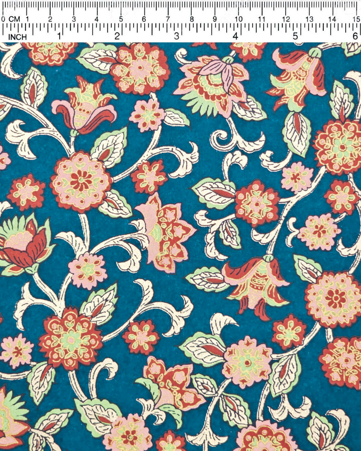 Japanese chiyogami paper featuring red, pink, and green sarasa flowers on a dark blue background with metallic gold details, shown next to a ruler for size reference.