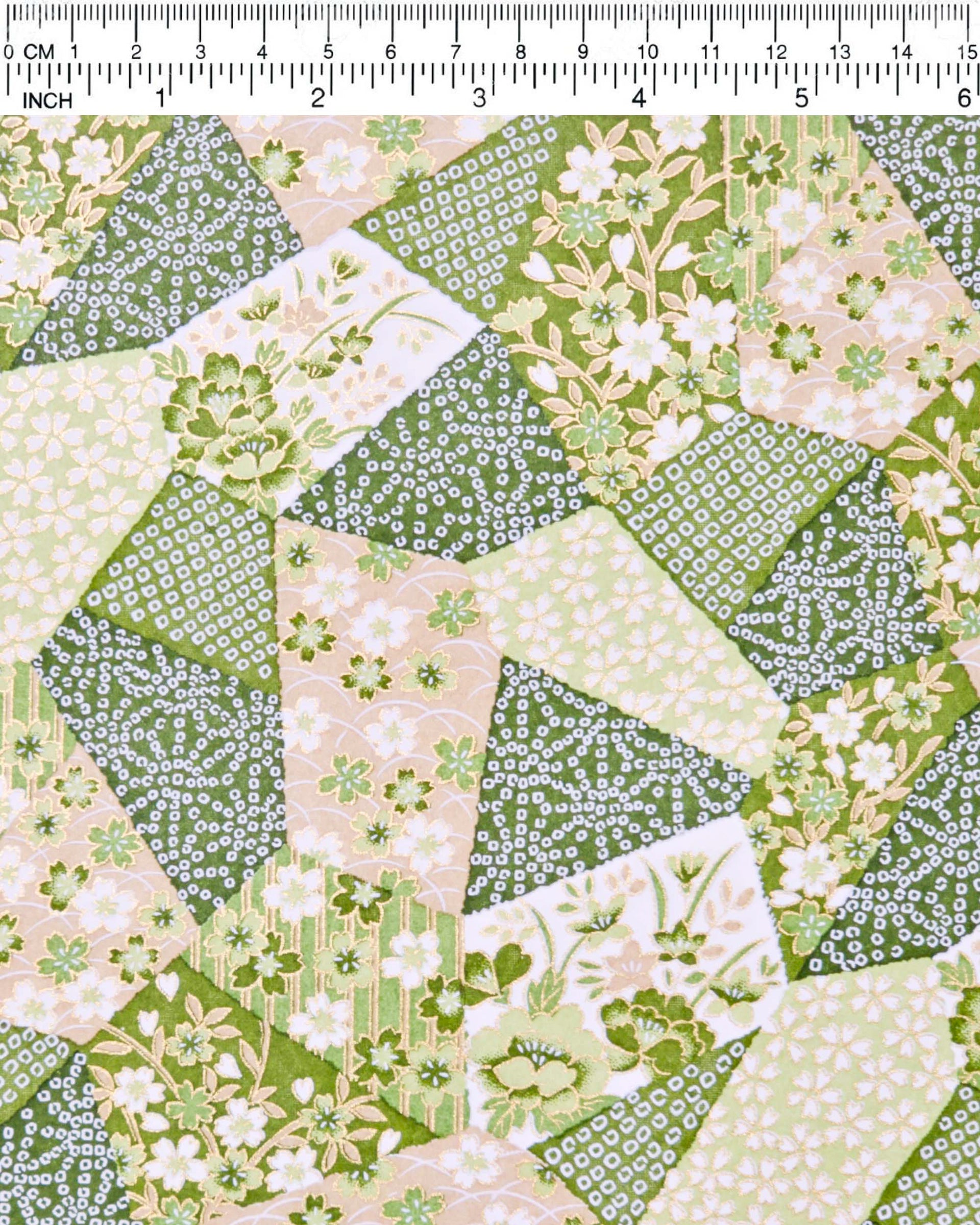 Japanese chiyogami paper featuring green, beige, and white floral patches embedded with assorted geometric and floral designs with metallic gold details, shown next to a ruler for size reference.