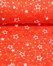 Japanese chiyogami paper featuring white assorted stars and smaller metallic gold stars and constellations on a red background, shown rolled to highlight the design.