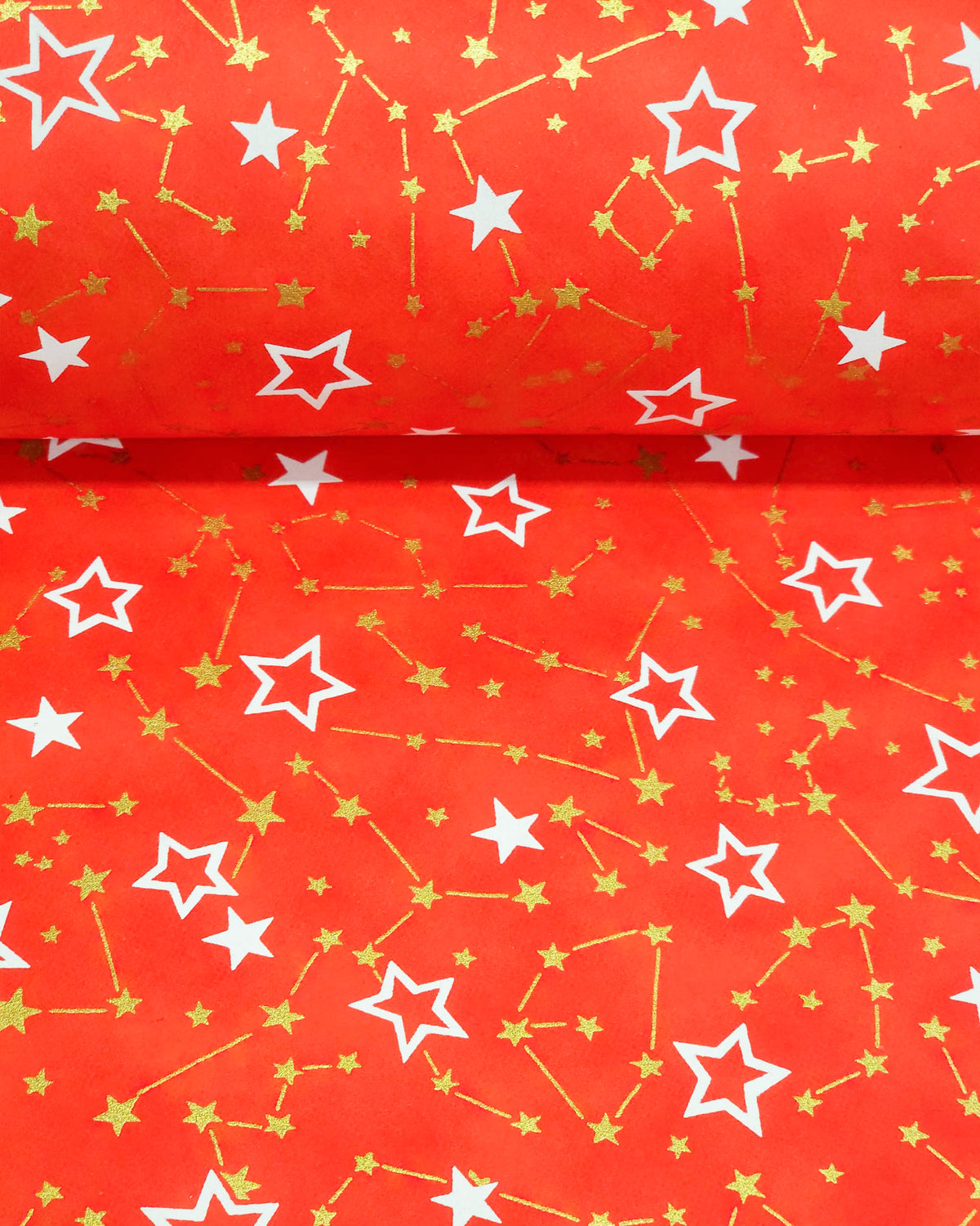 Japanese chiyogami paper featuring white assorted stars and smaller metallic gold stars and constellations on a red background, shown rolled to highlight the design.