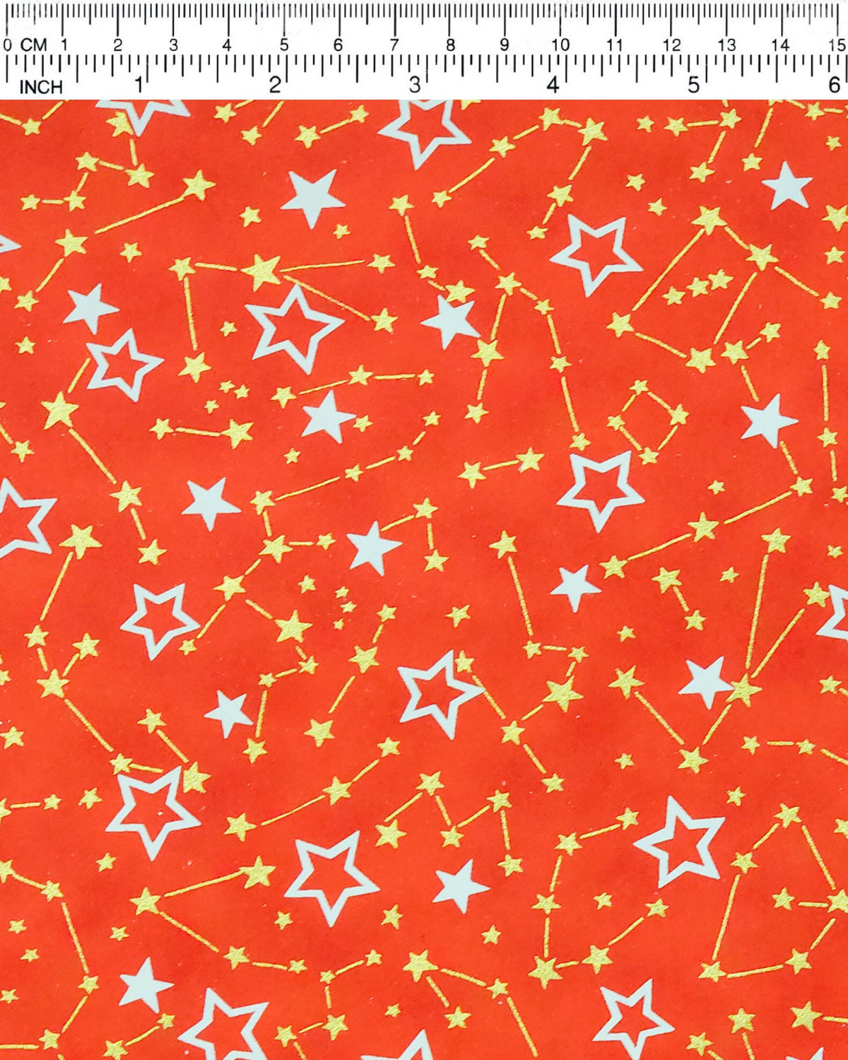 Japanese chiyogami paper featuring white assorted stars and smaller metallic gold stars and constellations on a red background, shown next to a ruler for size reference.