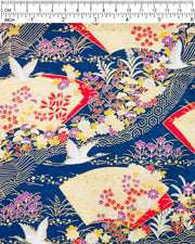 Japanese chiyogami paper featuring white flying cranes, gold and red folding fans, and assorted red, purple, white, and yellow flowers on a dark blue background with metallic gold wave and geometric details, shown next to a ruler for size reference.