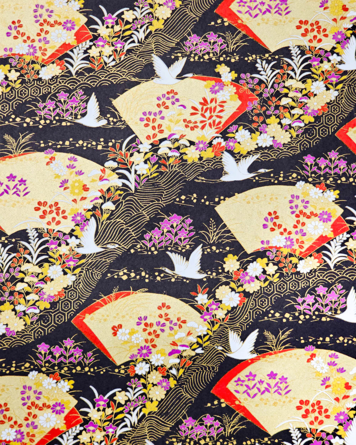 Japanese chiyogami paper featuring white flying cranes, gold and red folding fans, and assorted red, purple, white, and yellow flowers on a black background with metallic gold wave and geometric details.