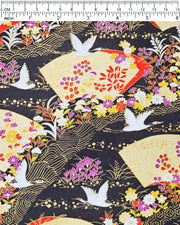 Japanese chiyogami paper featuring white flying cranes, gold and red folding fans, and assorted red, purple, white, and yellow flowers on a black background with metallic gold wave and geometric details, shown next to a ruler for size reference.