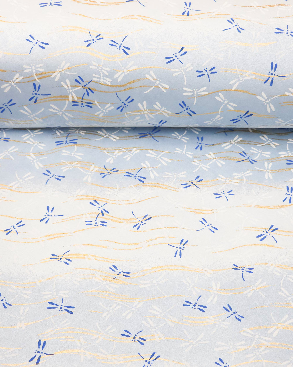 Japanese chiyogami paper featuring blue and white dragonflies on a pearlescent light blue gradient background with metallic gold wavy lines, shown rolled to highlight the design.