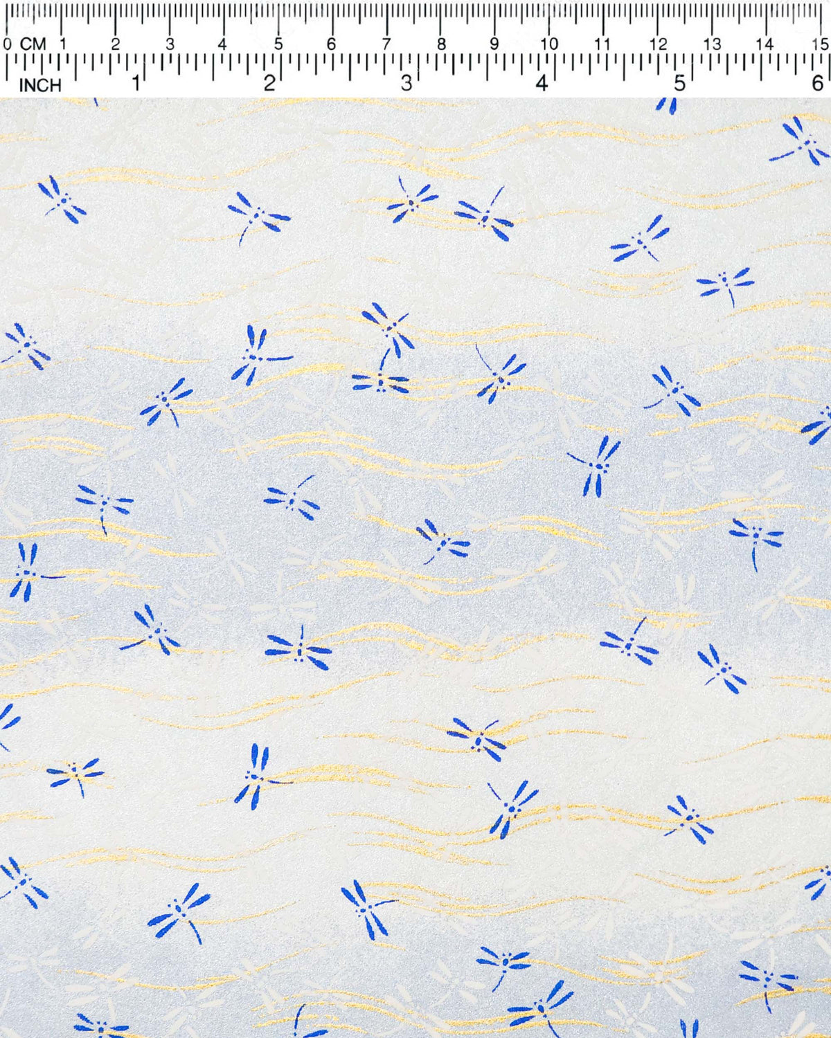 Japanese chiyogami paper featuring blue and white dragonflies on a pearlescent light blue gradient background with metallic gold wavy lines, shown next to a ruler for size reference.