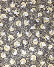 Japanese chiyogami paper featuring white rabbits with metallic gold moons, waves, and hagi bush clover on a black background.