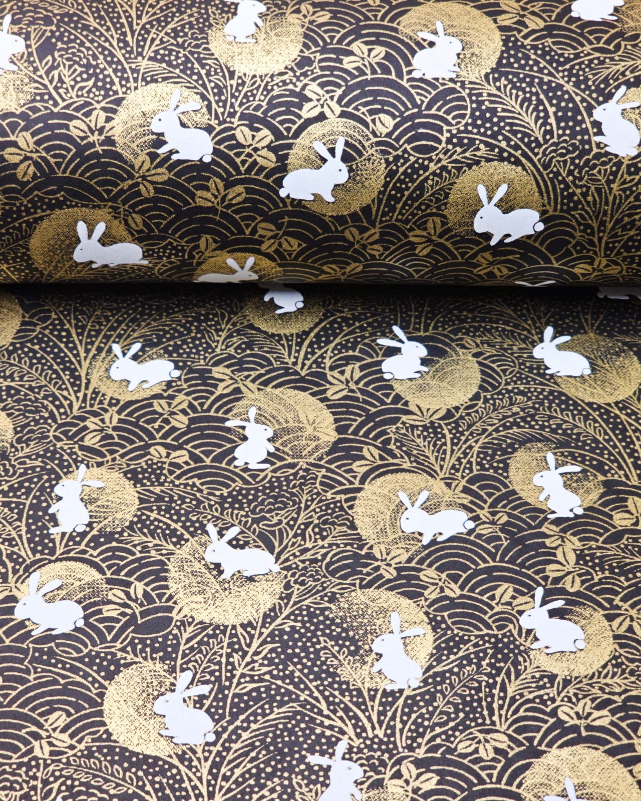 Japanese chiyogami paper featuring white rabbits with gold moons on a black background with metallic gold accents.