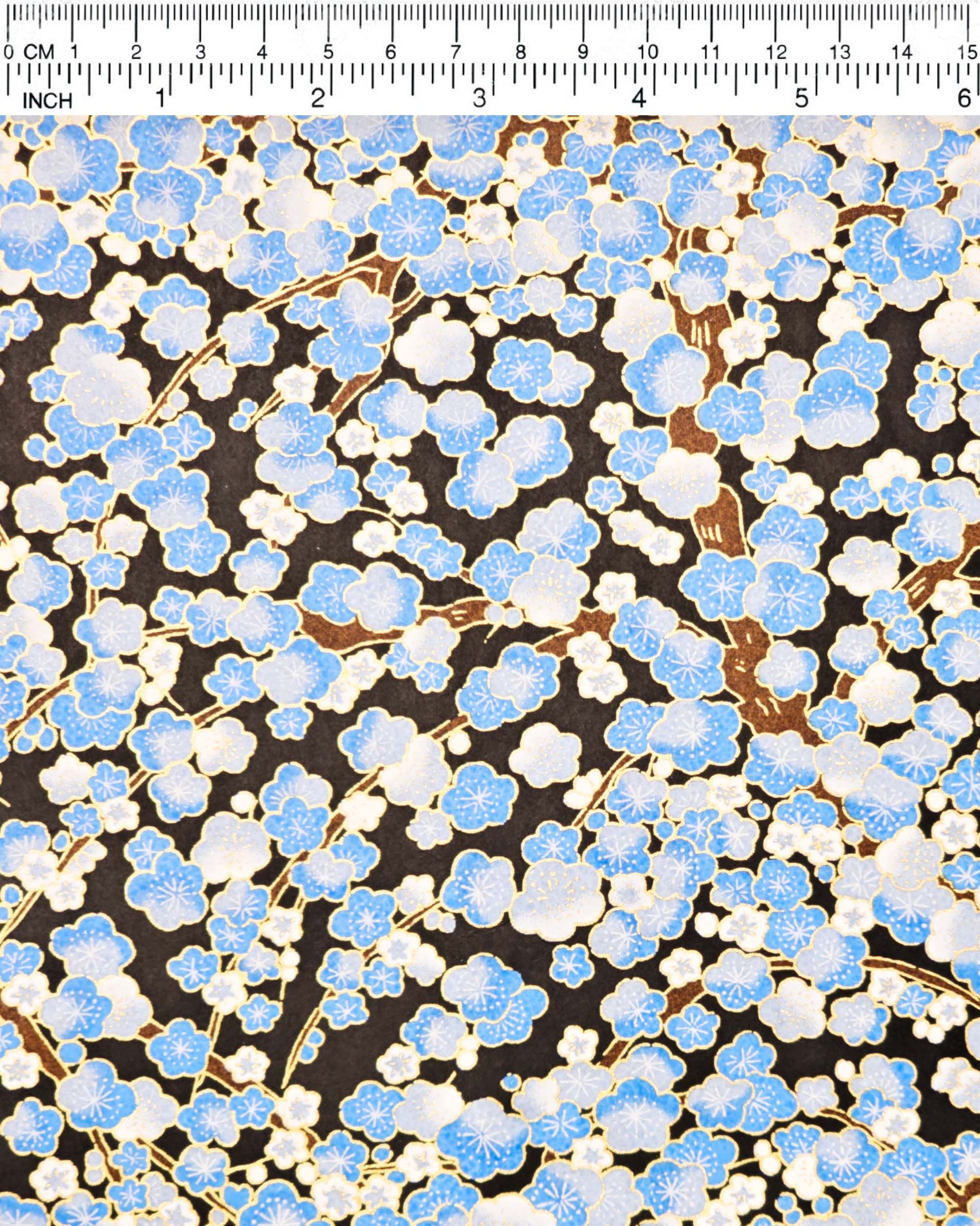 Japanese chiyogami paper featuring a blue plum blossom tree on a black background with metallic gold accents.