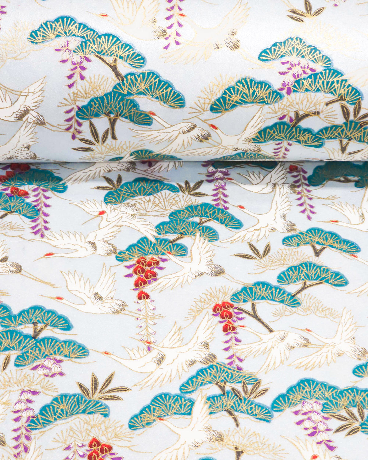 Japanese chiyogami paper featuring white flying cranes, purple and red wisteria, and green pine on a pearlescent light blue background with metallic gold details, shown rolled to highlight the design.