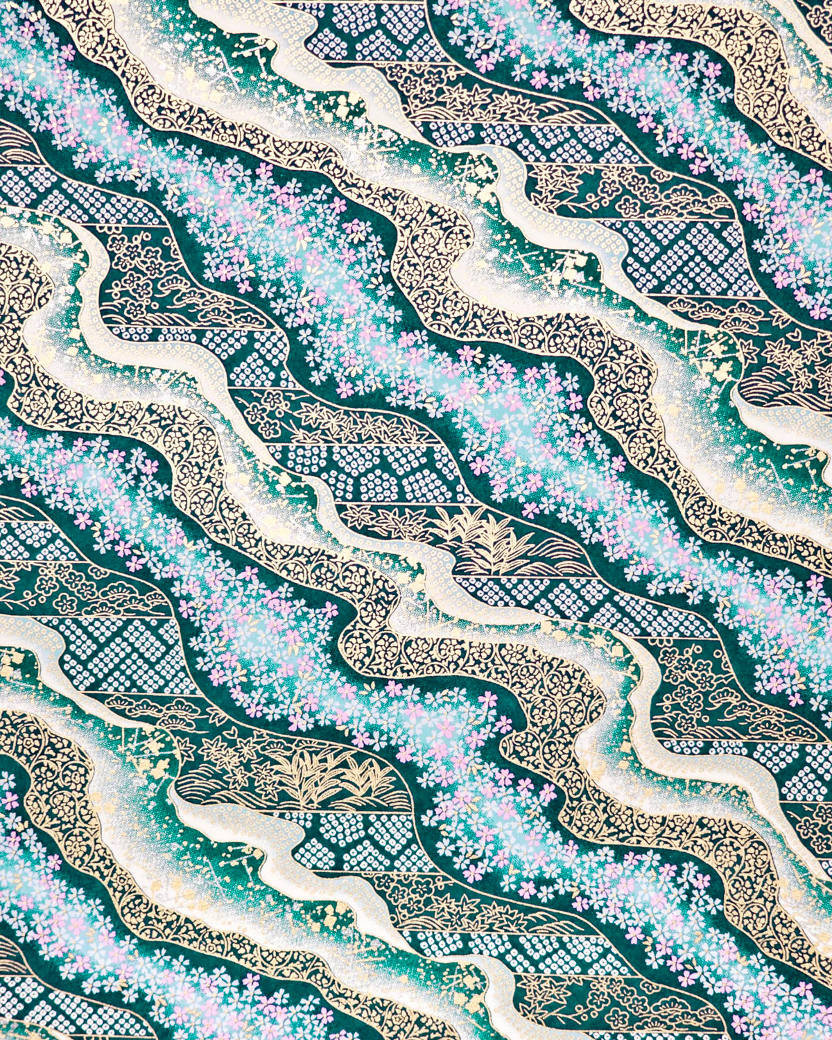 Japanese chiyogami paper featuring pink and white cherry blossoms with assorted traditional Japanese floral and geometric patterns on teal blue background with metallic gold and silver details.
