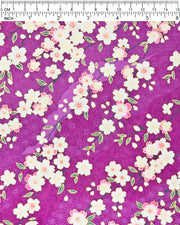 Japanese chiyogami paper featuring pink and white cherry blossoms on a purple background with light asanoha (hemp leaf) and small cherry blossom silhouettes and metallic gold details, shown next to a ruler for size reference.
