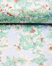 Japanese chiyogami paper featuring green and white leaves with metallic silver leaves on a light blue background with metallic gold details, shown rolled to highlight the design.